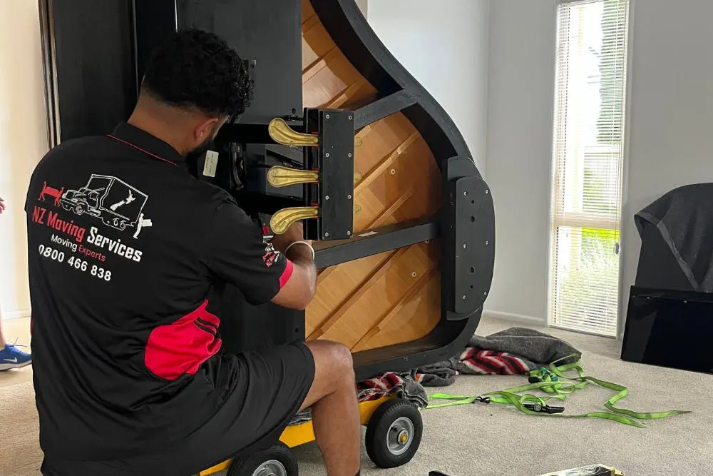 Expert piano movers disassembling a piano for transport